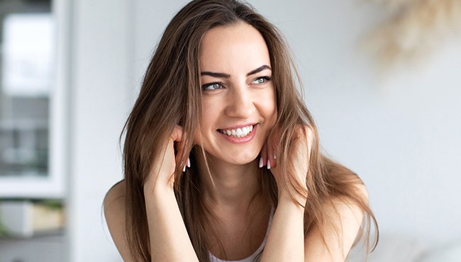 woman resting face on hands smiling